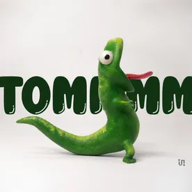 Tommm, a bright-green hand-painted lizard balanced on its tail.